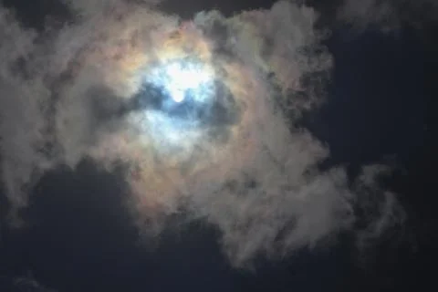 Sun Shining Through Dramatic Dark Clouds with Iridescent Edges 库存照片