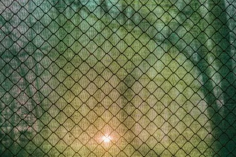 Sun shining through the green net and a fence Stock Photos