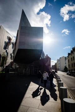 Sun shining through modern architecture building with people walking on the s Stock Photos