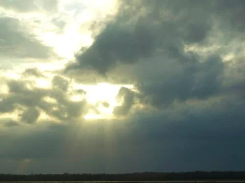 Sun shining through  storm clouds over a country field Foto stock