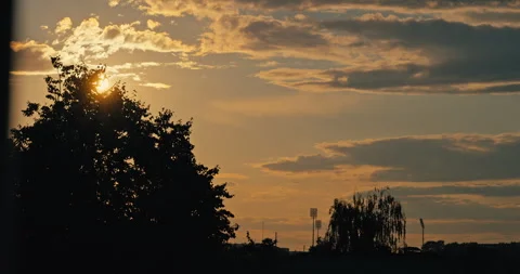 Sun Shining Through Trees Beneath Dramatic Evening Clouds Stock Footage 340856999