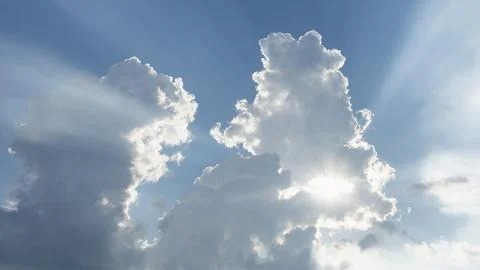 Sun shining through white puffy clouds Stock Photos
