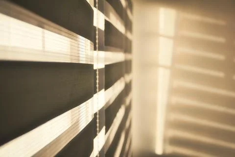 Sun shining through window blinds throwing shadows on the wall Stock Photos