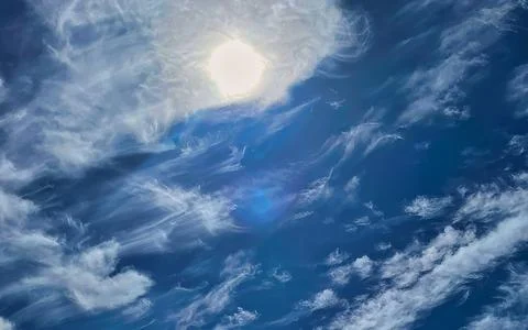 Sun shining through wispy clouds across a deep blue sky providing a sense o.. Stock Photos