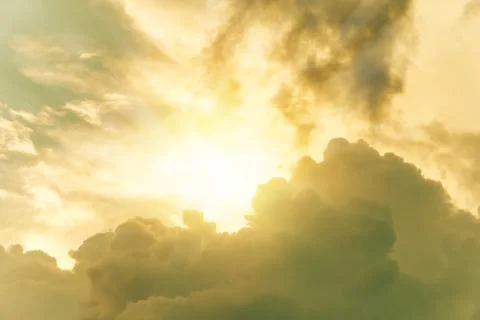 Sun shining through yellow dramatic clouds in sky Stock Photos