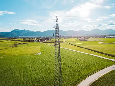 Sun is shining trough the clouds over the electrical tower in the middle of Stock Photos