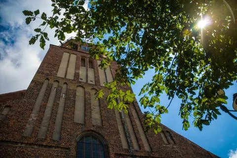 Sun shining true a tree in front of ancient church Stock Photos