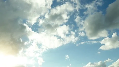 Sun shins bright in to the cloudy blue sky - timelapse - 4k Stock Footage 80052306