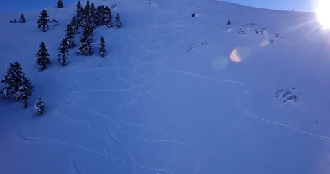 Sun shows over ski tracks zoom in shadow on steep off piste slope Stock Footage 93455519