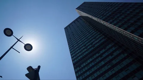 Sun sits behind lamp next to skyscraper in city artistically Stock Footage 110983522