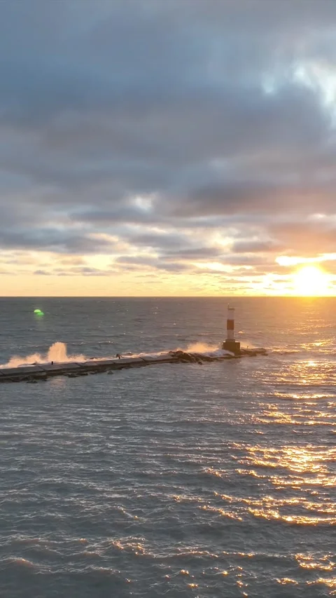 Sun slowly rises on a dark cloudy morning over the breakwall on Lake Michigan Stock Footage 265708327