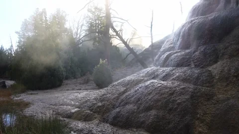 Sun streams through the morning steam as hot water rolls down travertine Stock Footage 299647497