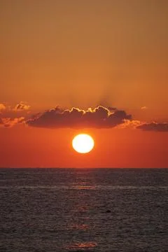 Sun at sunset between a cloud and the sea Stock Photos