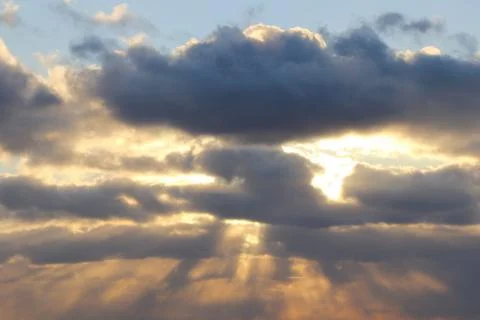 The sun at sunset or dawn behind the clouds, shines through. The sun's rays i Stock Photos
