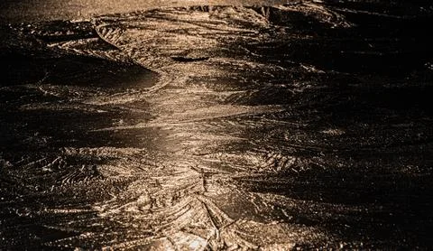 Sun on the texture of ice of a winter lake in a dark key Foto stock