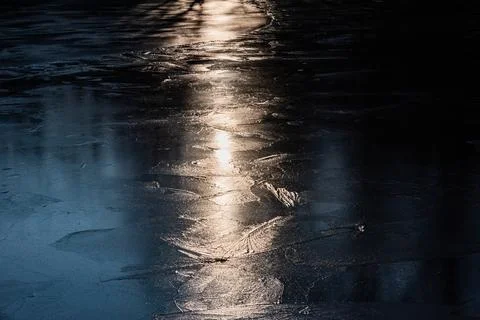 Sun on the texture of ice of a winter lake in a dark key Foto stock
