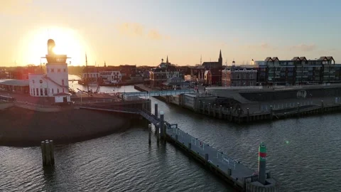 Sun threading behind round harbor building at dawn Stock Footage 331842216