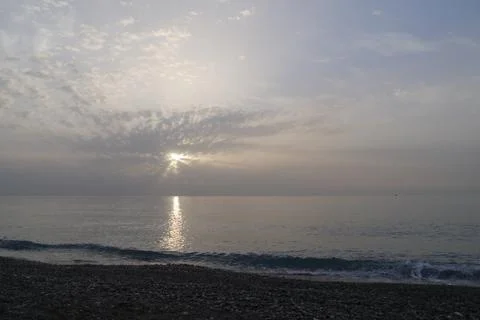 Sun through clouds during sunrise on the sea Stock Photos