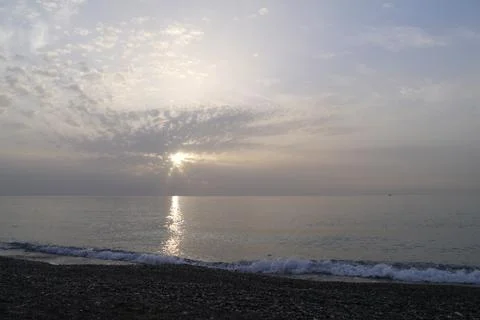Sun through clouds during sunrise on the sea Stock Photos