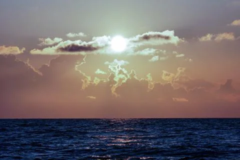 The sun through the clouds sits on the horizon Stock Photos