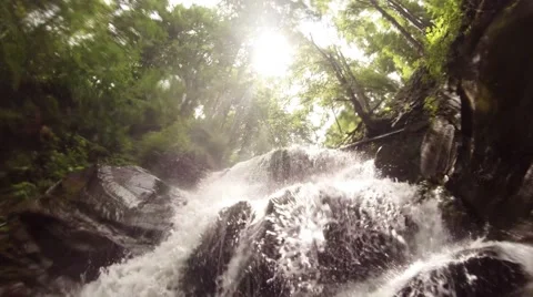 Sun through the spray of the waterfall falls on the rocks in the forest Stock Footage 43938772