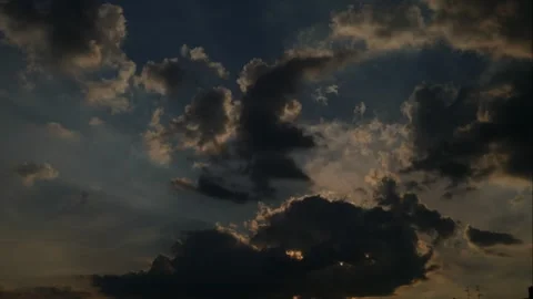 The sun tries to break its rays through the floating, broken, dark clouds Stock Footage 273588830