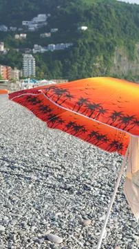 Sun umbrella on the pebble beach. Stock Photos