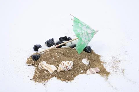 Sun umbrella with sunlight shadow on different sea shells and white stones. Stock Photos