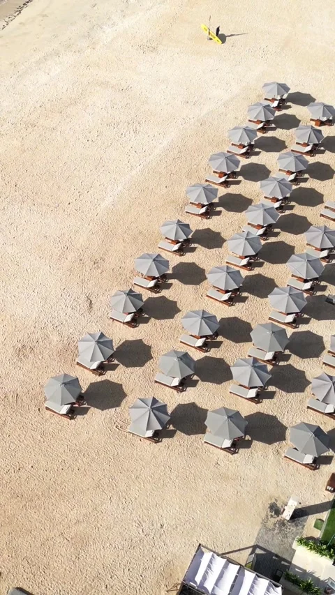 Sun umbrellas at the empty beach at morning time, Drone point of view.Vertical v Stock Footage 311942936
