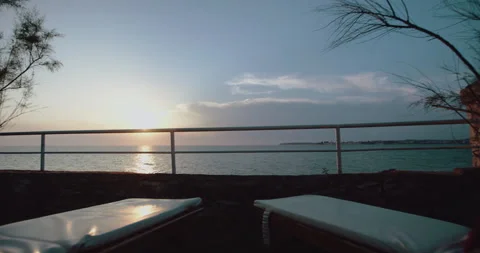 Sunbathing chairs overlooking a view of the sunset over the ocean Stock Footage 254769759