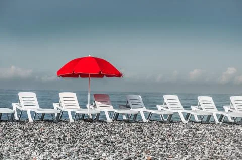Sunbathing plastic beds and red umbrella on the beach Stock Photos