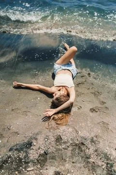 Sunbathing on a sandy beach while the waves wash over the shoreline on a su.. Stock Photos
