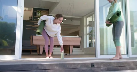 Sunbeam drawing two female friends carrying bottle and yoga mats onto deck Stock Footage 341467516