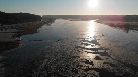 Sunbeam On Melting Ice On River, Reflection On Surface, Sunset, Pull Back Aerial Stock Footage 155329004