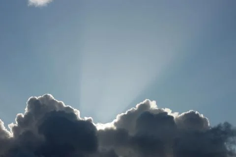 Sunbeam over dark clouds on the blue sky background Stock Photos
