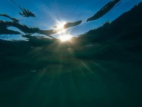 Sunbeam Shine through the surface of the blue water at the depth Stock Photos