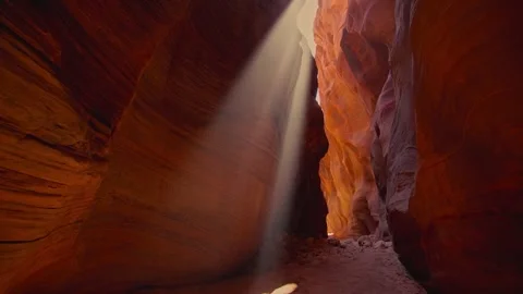 Sunbeam shining down into narrow slot canyon with glowing red sandstone walls Stock Footage 340076973