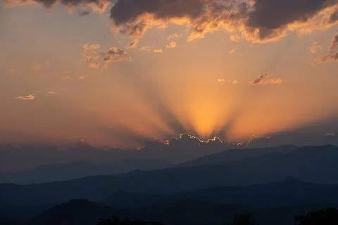 Sunbeams Breaking Through Clouds Above Mountain Range at Sunset. Stock Photos