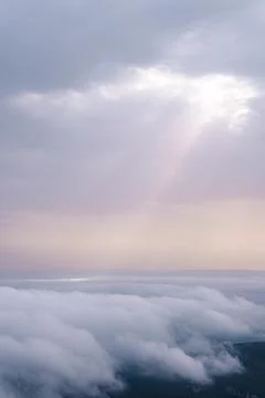 Sunbeams breaking through the clouds and impacting on top of other clouds. Stock Photos
