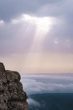 Sunbeams breaking through the clouds and impacting on top of other clouds. Stock Photos
