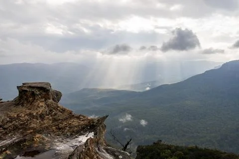 Sunbeams breaking through clouds on deep rugged valley and rolling hills Stock Photos