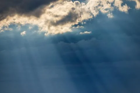 Sunbeams breaking through dark clouds at sunset. Stock Photos