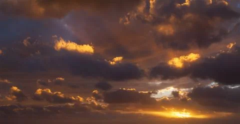 Sunbeams breaking through the dark clouds at sunset. Only sky, no land. Stock Photos