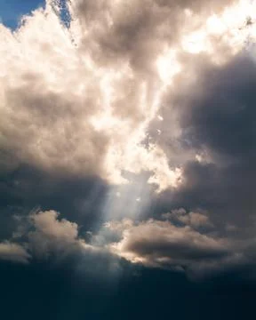 Sunbeams breaking through the dark clouds. Only sky, no land. Stock Photos