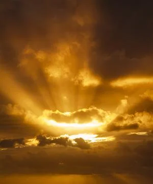 Sunbeams breaking through the dark clouds at sunset. Only sky, no land. Stock Photos