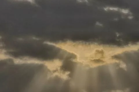 Sunbeams Breaking Through Dark Storm Clouds at Sunset Fotos de archivo
