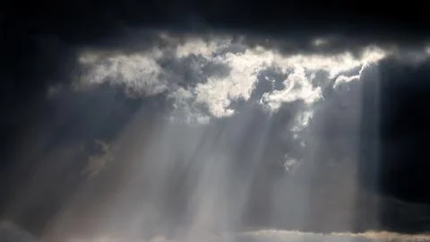 Sunbeams breaking through dramatic clouds, creating a striking, moody scene. Stock Photos