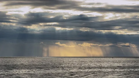 Sunbeams breaking through storm clouds over the ocean horizon Stock Footage 346011960
