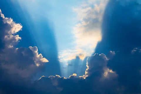 Sunbeams on a cloudy day or rays breaking out of clouds on a blue sky. Spirit Stock Photos