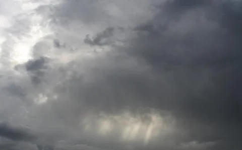 Sunbeams coming throughs the dark clouds under the sky. Stock Photos